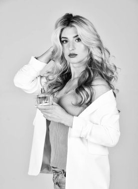 Kadınlık. Çekici kadın parfüm şişesini tutuyor. En sevdiği parfüm. Gençlik kokusu. Kadın parfümü konsepti. Parfüm cesur biri için yaratıldı. Uzun kıvırcık saçlı kız aromayla tatmin olmuş.