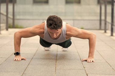 Beyaz tenli sporcu şınav çekiyor. Fitness antrenmanı. Açık havada şınav çek. Spor kıyafetli genç yakışıklı şınav çekiyor. Baldır ve kalça kasları için egzersiz yapıyor. mekik çeken yakışıklı adam.