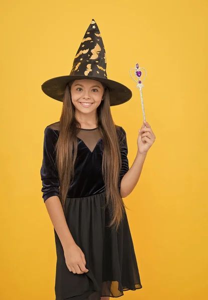 Igazán elbűvölő. A kölyök varázspálcát tart. Boszorkányság és varázslat. gyermekkori őszi nyaralás. tini lány kész ünnepelni party. jelmezes buli. Boldog Halloweent! mosolygó gyermek boszorkánykalapban — Stock Fotó