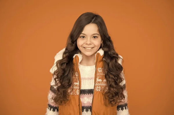 Menina adolescente feliz com cabelo encaracolado longo usar casaco de cintura puffer e suéter com padrões de Natal, roupas de inverno — Fotografia de Stock