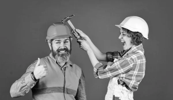 Concepto inteligible. Pareja renovando apartamento juntos. Un par haciendo reparaciones en casa. Hombre y mujer usan casco de seguridad. Renovación del hogar. Frótate. Un par golpeando la cabeza con martillo. Explicar claramente —  Fotos de Stock