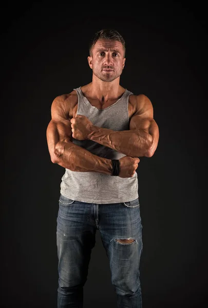 Atletisk man korsar starka muskulösa armar med biceps triceps muskler i casual slitage svart bakgrund, idrottsman — Stockfoto