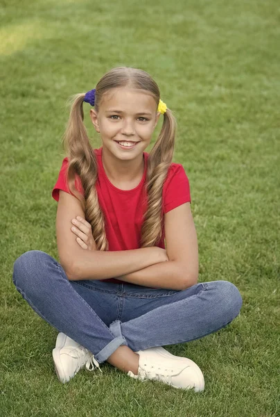 Little girl cute ponytails hairstyle relaxing on green grass, child care concept — Stock Photo, Image