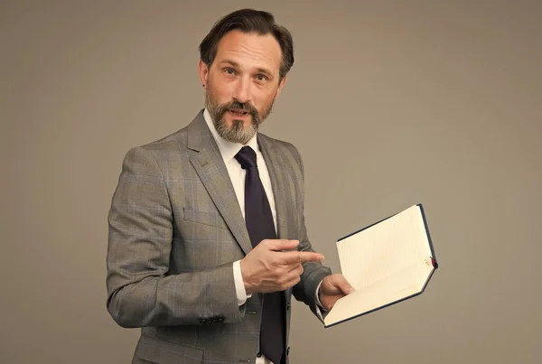 Get more knowledge. Bearded man point finger at open book. School teacher grey background. Making report. Presenting paper. Formal fashion style. Every book available here, copy space — ストック写真