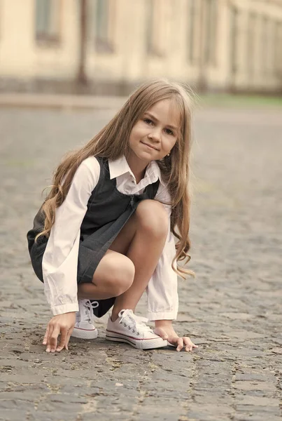 Bambino con i capelli lunghi in uniforme scolastica giocare in cortile della scuola all'aperto, infanzia — Foto Stock