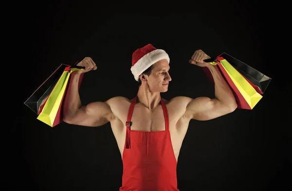 Fit Noel Baba, alışveriş çantalarını tut, kaslı kol kaslarını esnet, trisepsleri hazırla, Noel hazırlığı, güçlü. — Stok fotoğraf