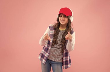 Şuna bak. Yeni teknoloji. Şapkalı ve kulaklıklı mutsuz genç kız. çocuk gündelik moda tarzı.