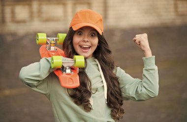 Powerslide tamamdır. Mutlu çocuk panoyu açık havada tutuyor. Penny binicisi. Aktif hobi. Denge ve hız. Peni tahtası sürüyorum. Kaykay yapmak. Sokak tarzı. Şehir kültürü. İtin ve hareket edin.