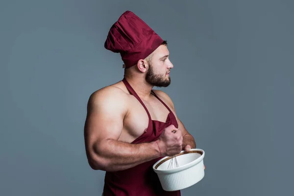 Athletic guy with strong muscles in chef apron cooking food, culinary — Stock Photo, Image