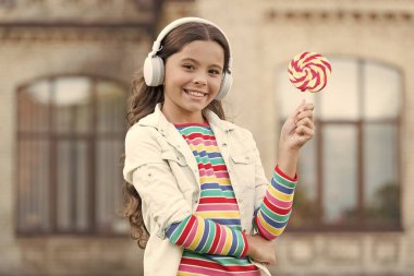 Kablosuz kız kulaklıkları lolipop yiyor, yaz tatili konsepti.