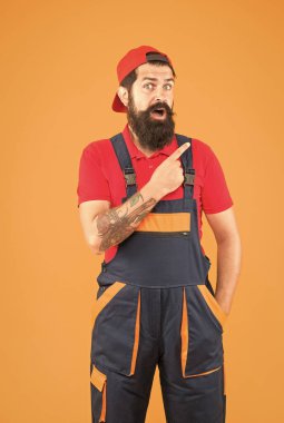 Sakallı, olgun bir işçi üniformalı, parmakla işaret ediyor.