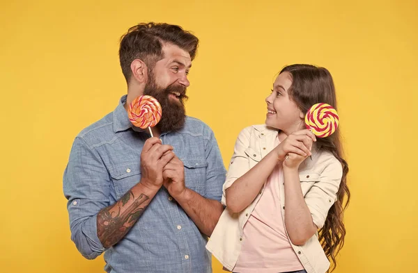 Gelukkig familie vader en dochter eten lolly gele achtergrond, suiker dieet concept — Stockfoto