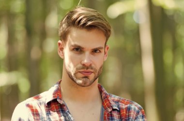 Sakallı, genç yüzlü, çekici bir adam. Teni ve şık saçları var. Yaz manzarasında sıradan bir tarzı var.