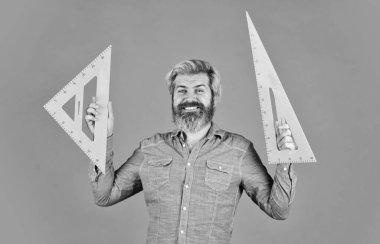 İşine odaklan. Eğitim. Okul öğretmeni üçgen kullanır. Matematik ve geometri dersi. Okula dönüyorum. Mühendisliğe hazır. Grafikler için araç. Olgun sakallı adam üçgen cetvel tutuyor. evde çalış.