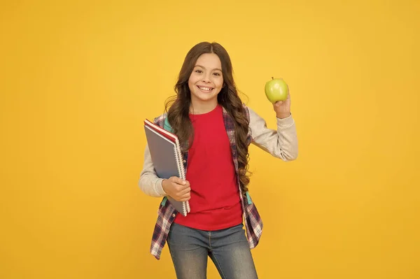 El futuro saludable comienza ahora. Chica feliz sostiene manzana y libros. Aperitivo escolar. Alimentación y dieta saludables. Nutrición con vitaminas. Hábitos alimenticios saludables. Natural y orgánico. Sé inteligente, come inteligente. — Foto de Stock
