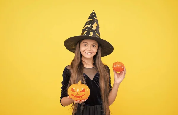 Criança feliz usar chapéu de bruxa segurando abóbora para criar jack o lanterna no dia das bruxas, tradição halloween feliz — Fotografia de Stock