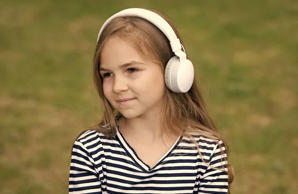 Cute little kid słuchać audio kurs języka w słuchawkach na zewnątrz, angielski — Zdjęcie stockowe