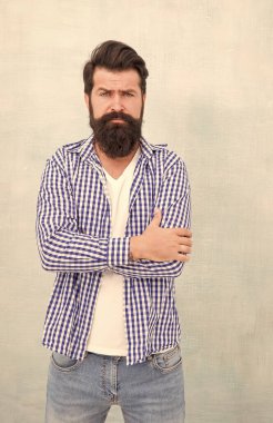 Tıraşsız sakallı, sıradan moda tarzı olan, kollarını çapraz mavi arka planda tutan hippi sakallı adam.