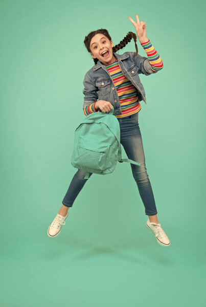 Добавление радости в праздники. Счастливая девушка прыгает синий фон. Маленький ребенок делает знак победы в воздухе. Школьные каникулы. Отдых и свободное время. Летние каникулы. Наслаждаюсь праздниками. Заполните трепет сегодня