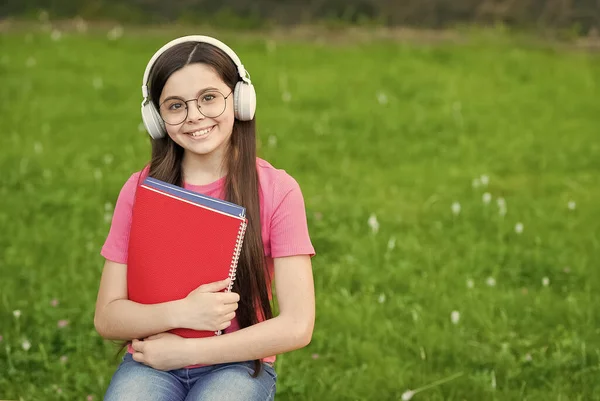 Affordable e-learning. Happy kid listen to e-learning course. Small girl study online outdoors. E-learning and study. Music lesson. Distance education. Remote training. E-learning is future