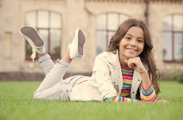 Buďte volní a v bezpečí. Šťastné dítě odpočívat na zelené trávě. Krásný vzhled holčičky. Kadeřnictví. Péče o děti a dětství. Volnočasové a hrací aktivity. Letní prázdniny. Mezinárodní dětský den — Stock fotografie