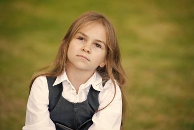 Uzun saçlı, ciddi bir çocuk. Moda okulu üniforması giyiyor.