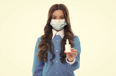 Koronavirüse karşı koruyucu maskeli sağlıklı bir çocuk covid pandemik ve karantina sırasında burun damlası sunar.