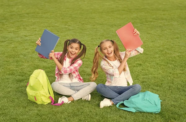 Simplement être dans le coin. trouver quelque chose d'intéressant dans le livre. prendre des notes. passer du temps libre après l'école. petits amis enfants se détendre sur l'herbe. retour à l'école. littérature pour les filles. faire des devoirs ensemble — Photo