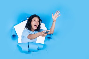 Mutlu kadın uzaktan kumandanın altına basıyor. Kız TV programı izliyor. Yeni teknolojiyi kullan. Akıllı ev kumandası. insan duygularını ifade etmek. Kadın televizyon izliyor. Boşluğu kopyala