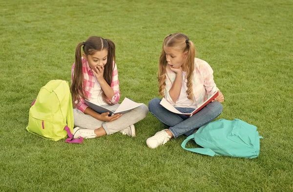 Faire des devoirs ensemble. trouver quelque chose d'intéressant dans le livre. prendre des notes. passer du temps libre après l'école. petits amis enfants se détendre sur l'herbe. retour à l'école. littérature pour filles — Photo