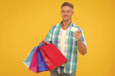 İş ya da kredi kartı olan bir adam. Mutlu adam alışveriş torbaları taşır. Kara Cuma. Paketlerle alışveriş yapan erkek. Tatil için hazırlanın. Noel satışları ve indirimler. Doğum günü hediyesi paketleri. Alışveriş koliği.