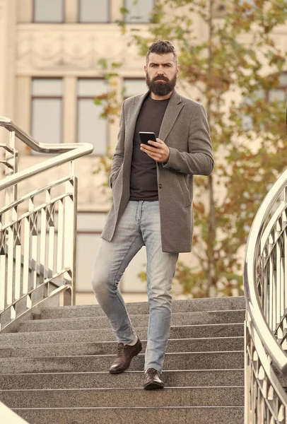 カジュアルなビジネススタイルで忙しいヒップスターは、屋外で携帯電話の都市を保持階段を歩いて、男 — ストック写真