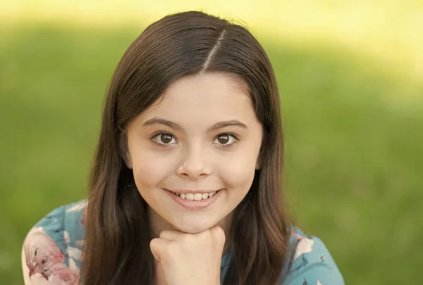 Menina com cabelos longos relaxante no parque ensolarado dia verde grama fundo, conceito sorriso adorável — Fotografia de Stock