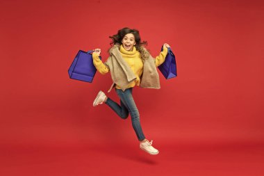 Alışveriş merkezinde başarılı bir günden sonra alışveriş paketleriyle koşan mutlu çocuk, mevsimlik indirimler.