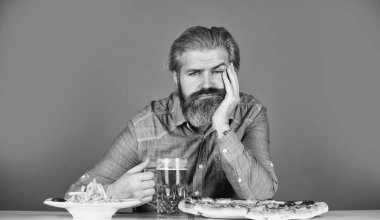Sıkılmış ve üzgün. Bira ve yemek. Barda akşam yemeği. Aç adam patates kızartması yiyecek ve bira içecek. Pizzacı. Üzgün sakallı hippi adam pizza yiyor. Pizza partisi konsepti. İştah