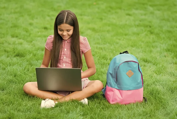 En lycklig grabb som jobbar på laptop. Internetutbildning. Tillbaka till skolan. tonåring flicka använder dator på grönt gräs i parken. barn med ryggsäck och anteckningsbok. Ny teknik i det moderna livet. Undersökning — Stockfoto