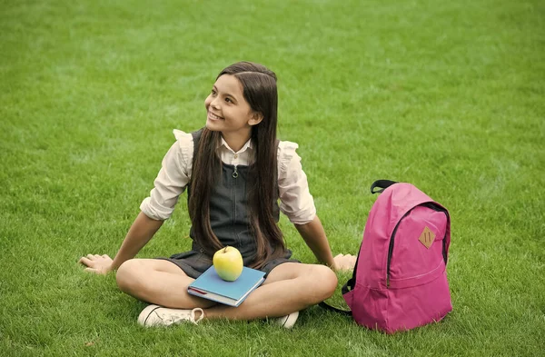 Gelukkig kind in schooluniform ontspannen met boek en appel gezond dieet op groen gras, dieet — Stockfoto