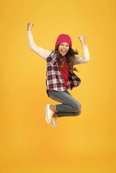 Mira hipster. niño alegre en sombrero de punto. estilo de moda de mezclilla. colegiala sobre fondo amarillo. lleno de energía. moda infantil y belleza. adolescente saltando en ropa de estilo casual. feliz infancia — Foto de Stock