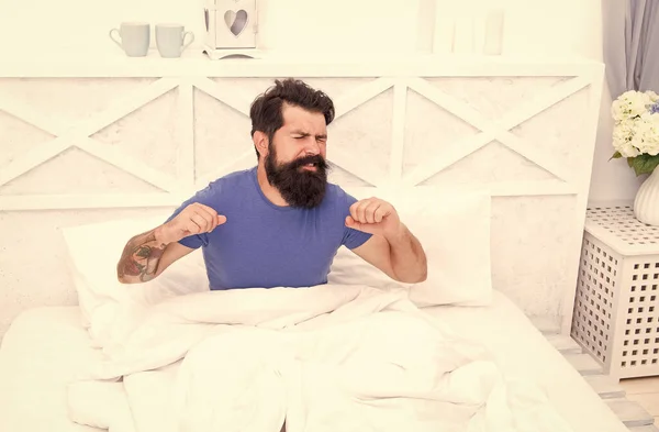 Homme caucasien avec barbe couchée sur le lit après avoir dormi dans une chambre lumineuse, étirement du matin — Photo
