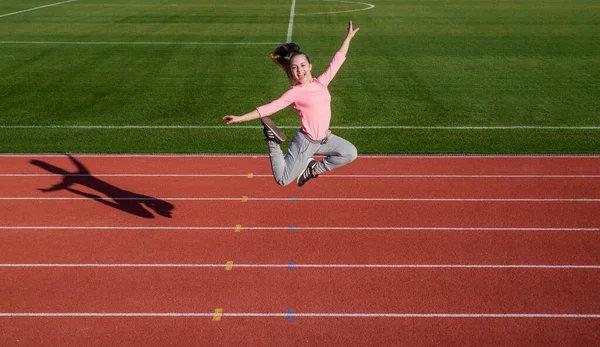 Happy energetic girl child jump on running track, athletics — Zdjęcie stockowe