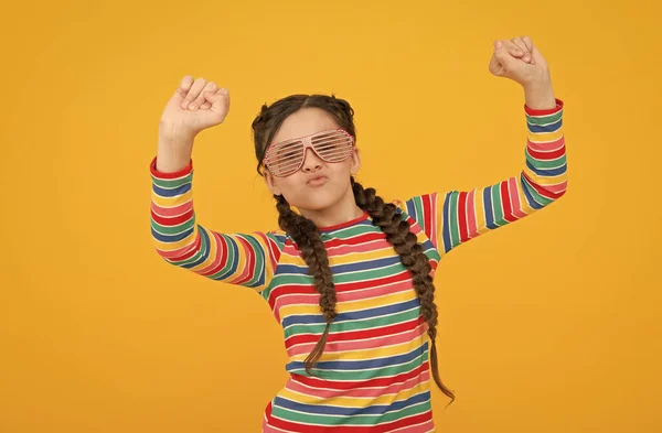 Eu consigo fazer isto. Miúdo engraçado a divertir-se. beleza em óculos de glamour. felicidade infantil. criança sorridente no fundo amarelo. acessório de moda casual. Hora da festa. menina adolescente feliz com penteado elegante — Fotografia de Stock