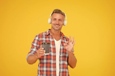 Mutlu adam, hazır kahve fincanı için el hareketi yap kulaklıkla müzik dinle, kahve götür.