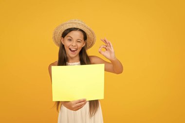 Yeni bir fikri paylaşıyoruz. Mutlu küçük kız boş kağıt tutuyor. kopyalama alanı. Sıcak tatil zamanı. Ilık ülkelere seyahat. Çocuk bahar modası. Hasır şapkalı kız. Reklam. Çocuk gezgin. Yaz alışverişi