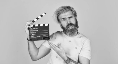 Oyuncu kadrosu. Çekim sahnesi. Favori dizisi. Başla. Sinema yapımı. Yaratıcı yapımcı. Sakallı adam film alkışlayıcısı tutuyor. Film yapma konsepti. Alkış tahtası kopyalama alanı. Film izle. Film yönetmeni