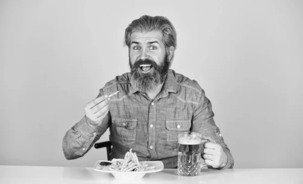 Ver futebol na TV. fast food americano. homem barbudo feliz com cerveja e batatas fritas. Batata frita. Um tipo no bar americano a beber um copo de cerveja e a comer batata. Saúde. — Fotografia de Stock