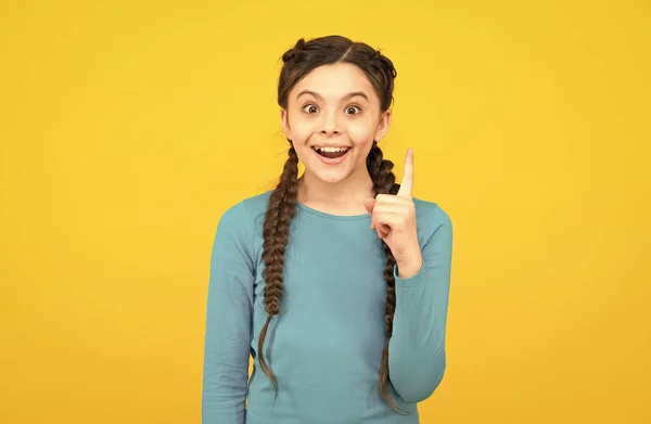 Inspiré heureux adolescent fille avec des cheveux tressés a une idée sur fond jaune, créativité — Photo