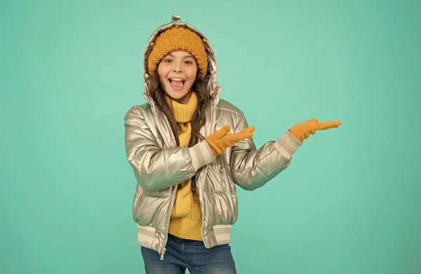 Sorrindo criança elegante apresentando produto, espaço de cópia. outono compras temporada. Menina adolescente em jaqueta de prata. roupas quentes da moda. loja de acessórios para criança. desfrutar do tempo em feriados de Natal — Fotografia de Stock