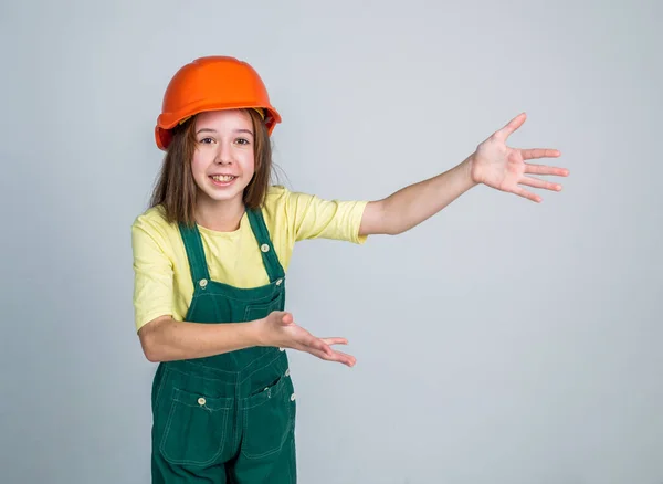 Teen girl laborer in protective helmet and uniform showing copy space, gesturing — Foto de Stock