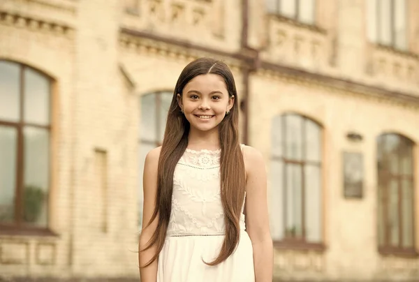 Criança feliz cabelo longo sorridente rosto urbano fundo ao ar livre, conceito dia das crianças — Fotografia de Stock