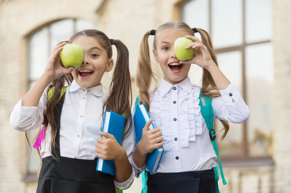 Eso es grandioso. hora del almuerzo en el recreo escolar. niños felices en uniforme. aprender juntos el tema. educación moderna para las niñas. lectura de libros. concepto de amistad. pequeño alumno con cuaderno y manzana — Foto de Stock